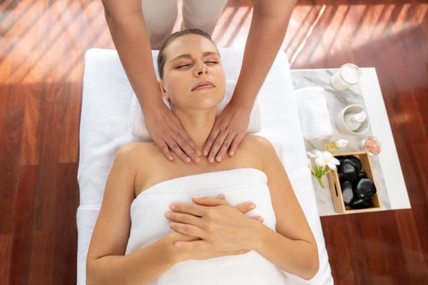 Une femme reçoit un massage relaxant dans un spa, allongée sur une table de massage, entourée d'une ambiance apaisante.
