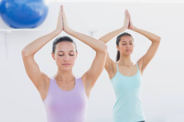 Deux femmes pratiquant le yoga dans une salle de sport, concentrées et en pleine séance d'exercice.