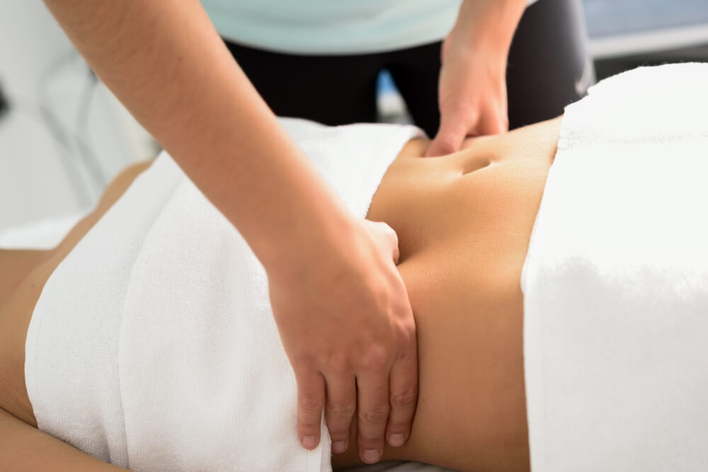 Une femme reçoit un massage relaxant dans un spa, allongée sur une table de massage, entourée d'une ambiance apaisante.